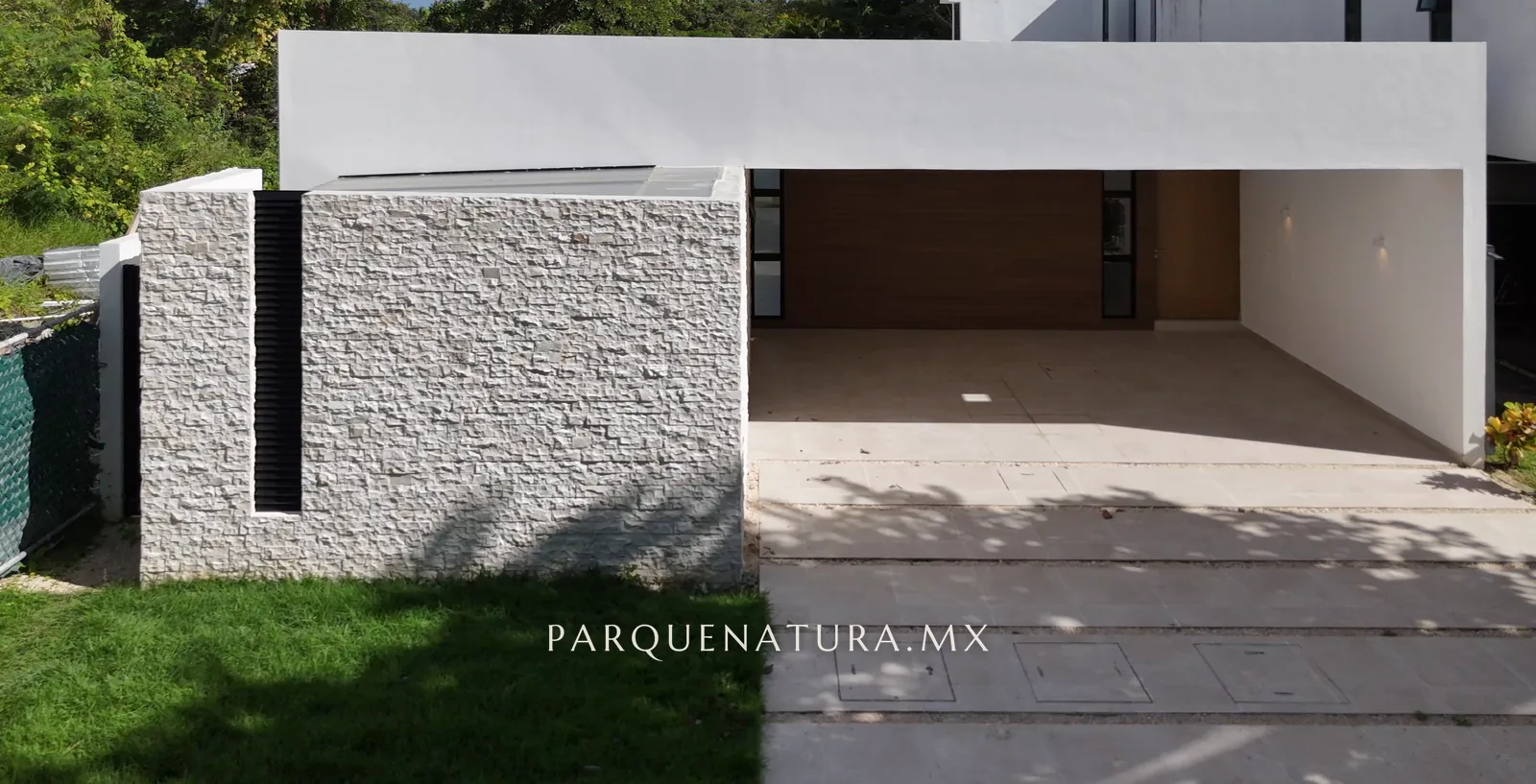 Fachada de la Casa 208 con muro de piedra y cochera techada