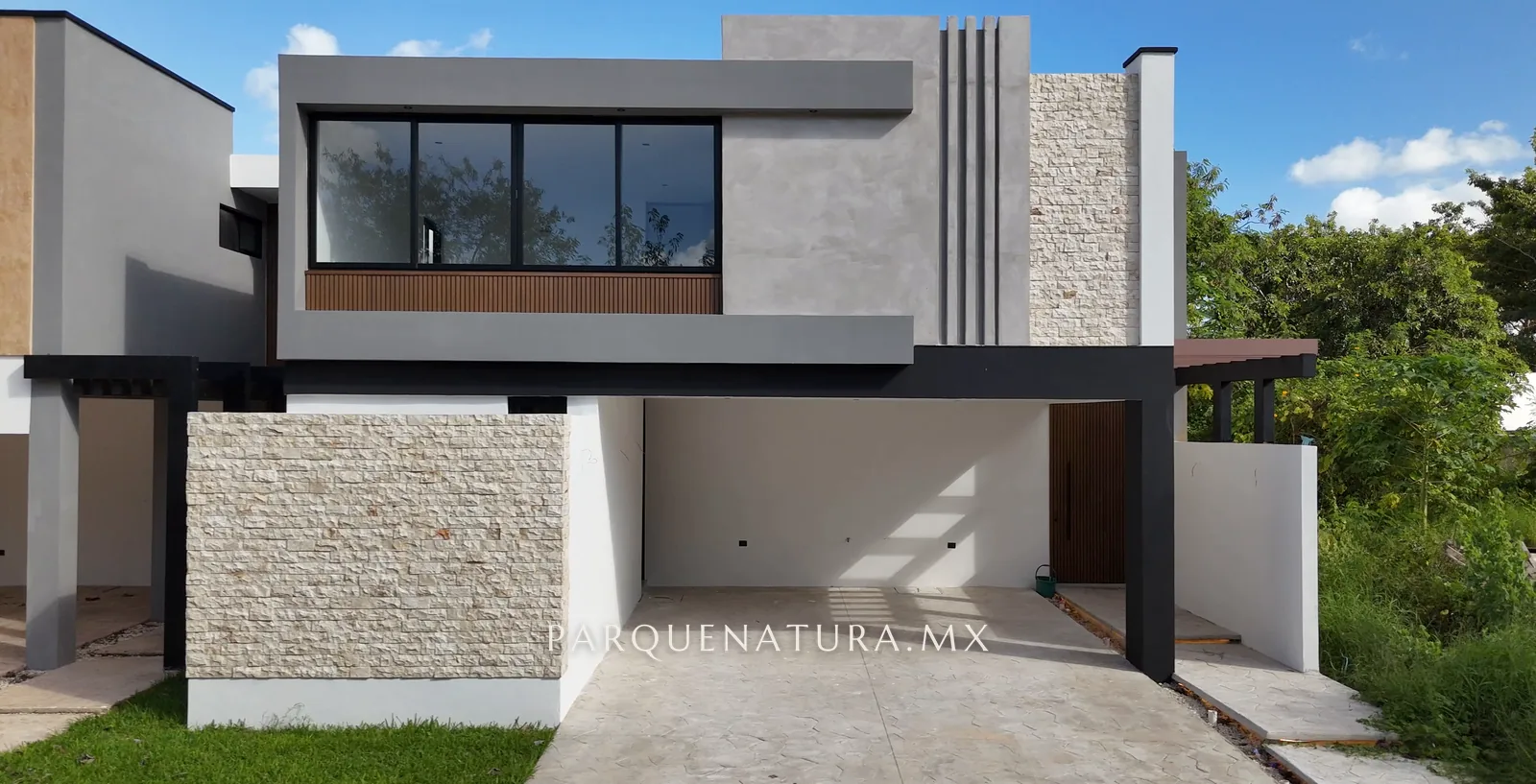 Fachada de la Casa 210 con muro de piedra, estrías y cochera techada