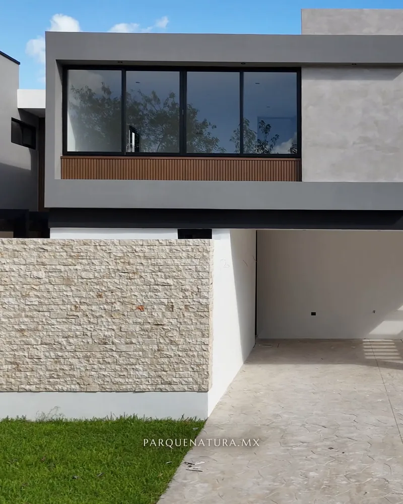 Fachada de la Casa 210 con muro de piedra, estrías y cochera techada